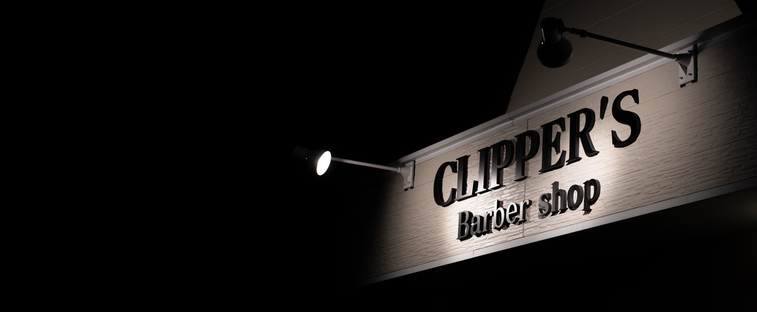 夜、灯りに照らされたCLIPPER'S Barber shopの店頭サイン